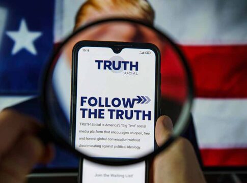 Phone displaying Truth Social app over American flag background.