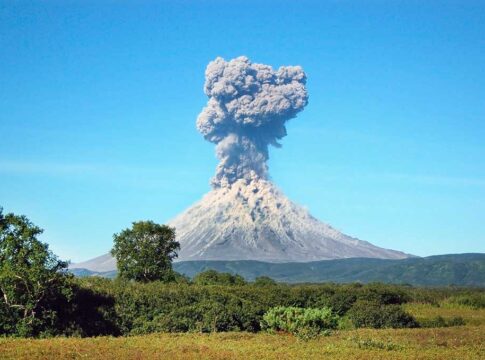 Volcano erupting with thick smoke plume.