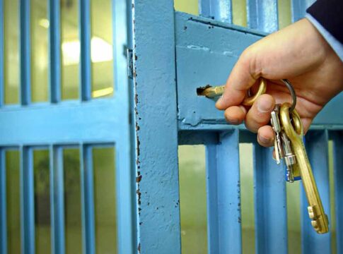 Hand unlocking a metal gate with keys.
