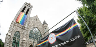 Church with rainbow flag and welcoming sign for LGBTQ+.