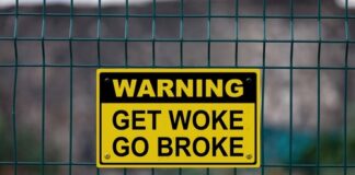Warning sign Get Woke Go Broke on fence