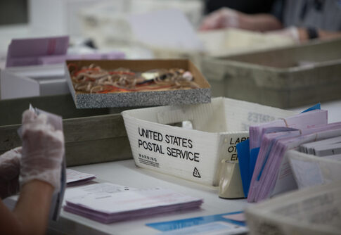 USPS worker handling mail-in ballots at a sorting facility