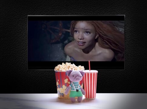 Stuffed toy with popcorn, soda, TV displaying mermaid scene.