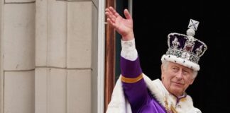 King Charles III in coronation attire waving.