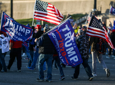 People holding Trump flags and American flags rallying