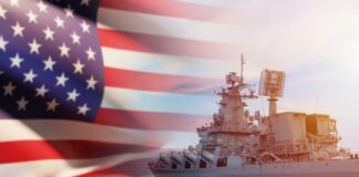 US flag and navy warship in the background.