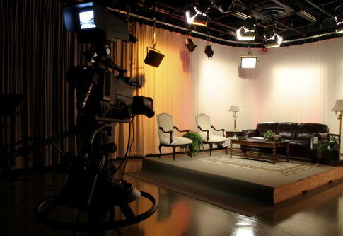 Empty TV studio set with chairs and a sofa.