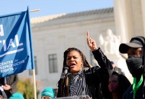 A woman speaks passionately at a public rally.