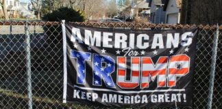Americans for Trump banner on a fence with flags