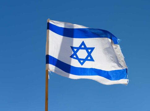 Israeli flag waving against a clear blue sky.