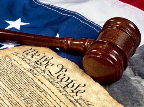Gavel and Constitution on American flag background.