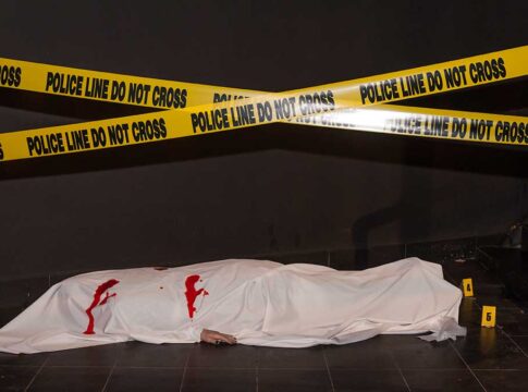 Body under white sheet with police line tape.