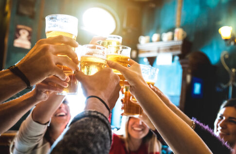 People toasting with beer in a bar.
