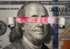 Torn dollar revealing Chinese yuan behind Benjamin Franklin's eyes.