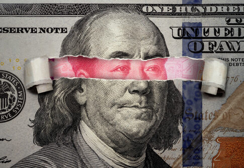 Torn dollar revealing Chinese yuan behind Benjamin Franklin's eyes.