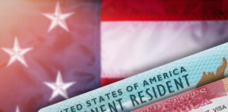 Green card and visa with U.S. flag background.