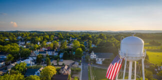 Water tower with American flag overlooking a small town.