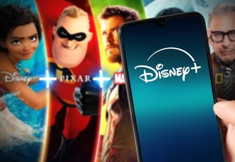 Disney+ logo on phone with movie characters background.