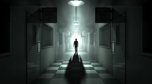 Silhouette in dimly lit hallway with room signs.