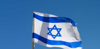 Israeli flag waving against a clear blue sky.