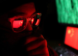 Person wearing glasses reflecting Chinese flag, green code.