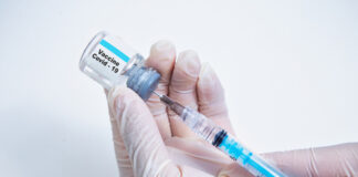 Hands holding Covid-19 vaccine vial and syringe.