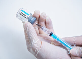 Hands holding Covid-19 vaccine vial and syringe.