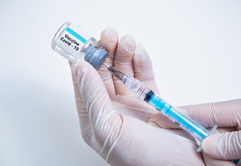 Hands holding Covid-19 vaccine vial and syringe.