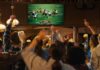 People cheering while watching football game in a bar.