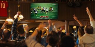 People cheering while watching football game in a bar.