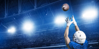 Football player catching a ball in well-lit stadium.