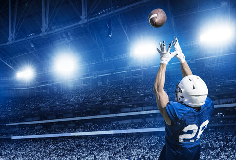 Football player catching a ball in well-lit stadium.