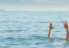 Persons hands above water in the ocean.