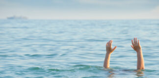 Persons hands above water in the ocean.