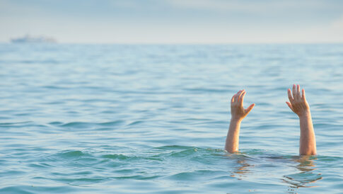 Persons hands above water in the ocean.