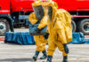 Workers in hazmat suits carrying a black container.