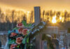 Wooden cross with flowers at sunset in a cemetery.