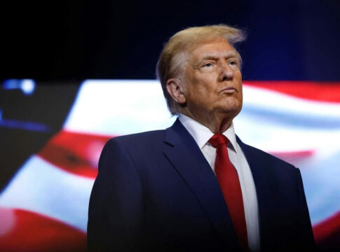 donald trump in suit with red tie American flag backdrop