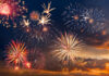 Colorful fireworks display against a darkening evening sky.