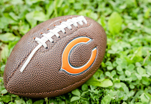 Football with Chicago Bears logo on grass.