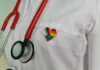 Doctor's coat with stethoscope and rainbow heart badge.