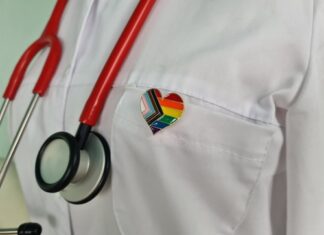Doctor's coat with stethoscope and rainbow heart badge.