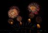 Fireworks display in the night sky over water.