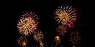 Fireworks display in the night sky over water.