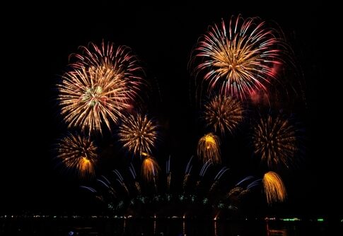 Fireworks display in the night sky over water.
