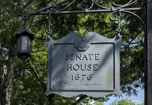 Historic Senate House sign from 1676 surrounded by trees