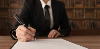 Person signing a document with a pen.