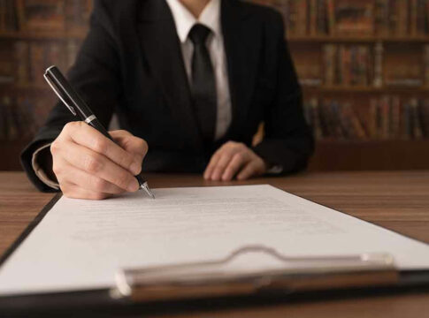 Person signing a document with a pen.