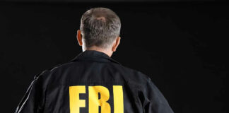 Man wearing FBI jacket, facing away.