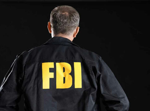 Man wearing FBI jacket, facing away.